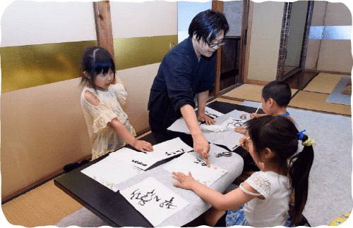 教室の様子。先生と小学生くらいの子供たち。